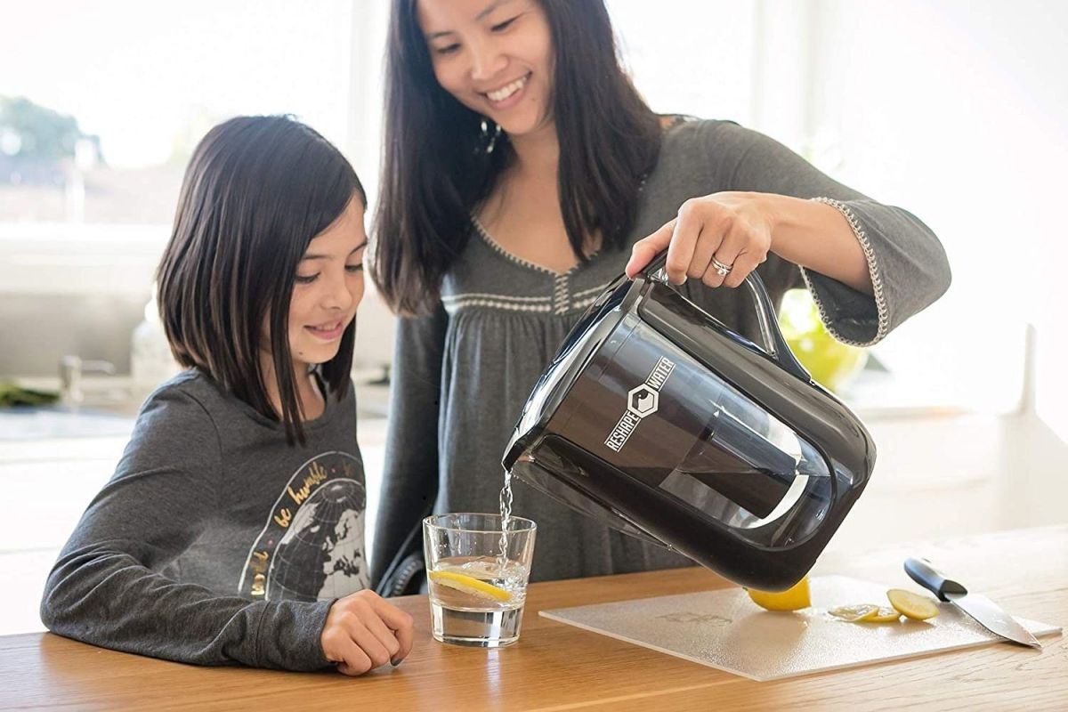 A mother pours a glass of water for her daughter from the best alkaline water filter pitcher option