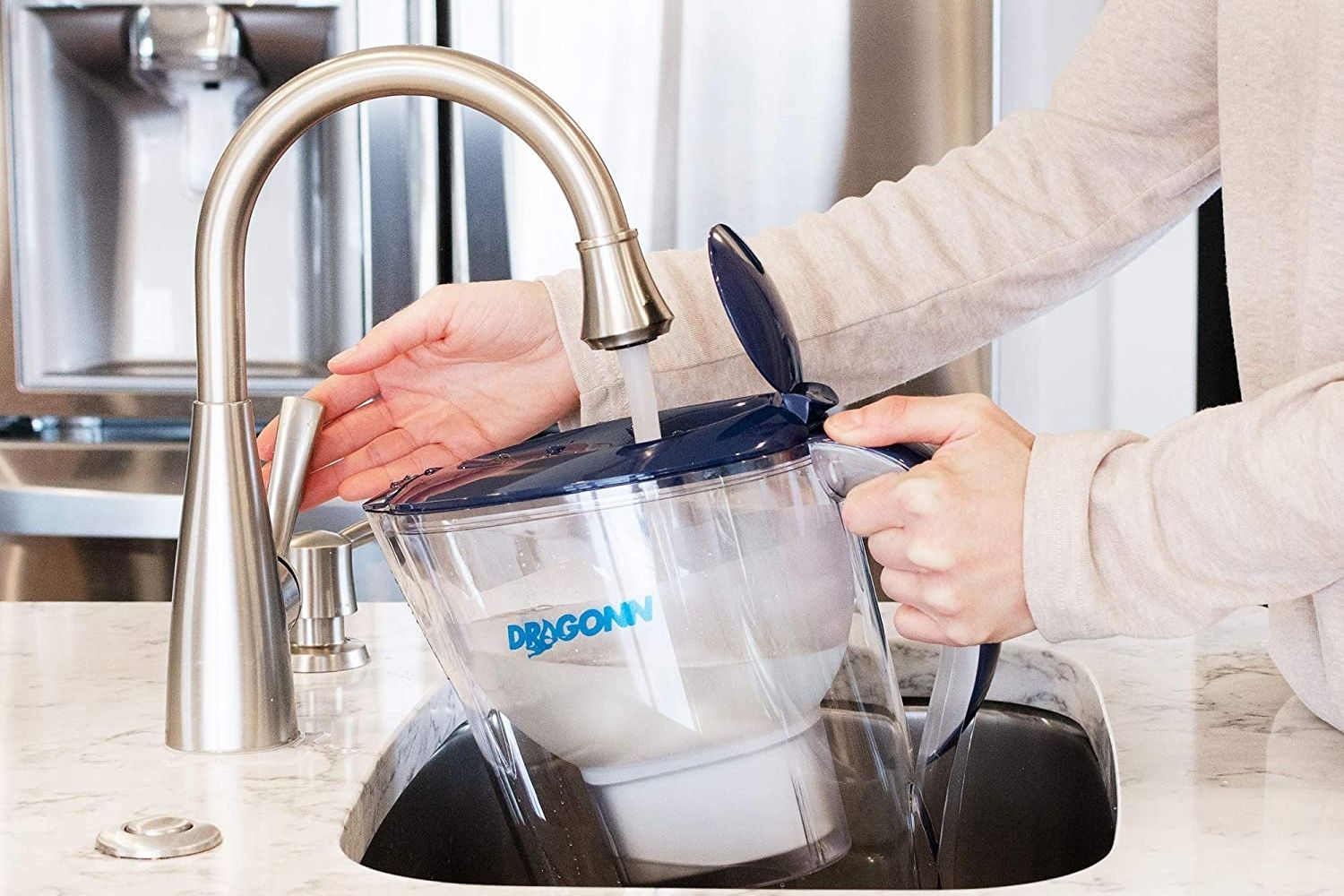 A person fills the best alkaline water filter pitcher at a kitchen sink