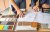 Cropped photo of two people's hands with blueprints, kitchen tile and color swatch samples on a table.