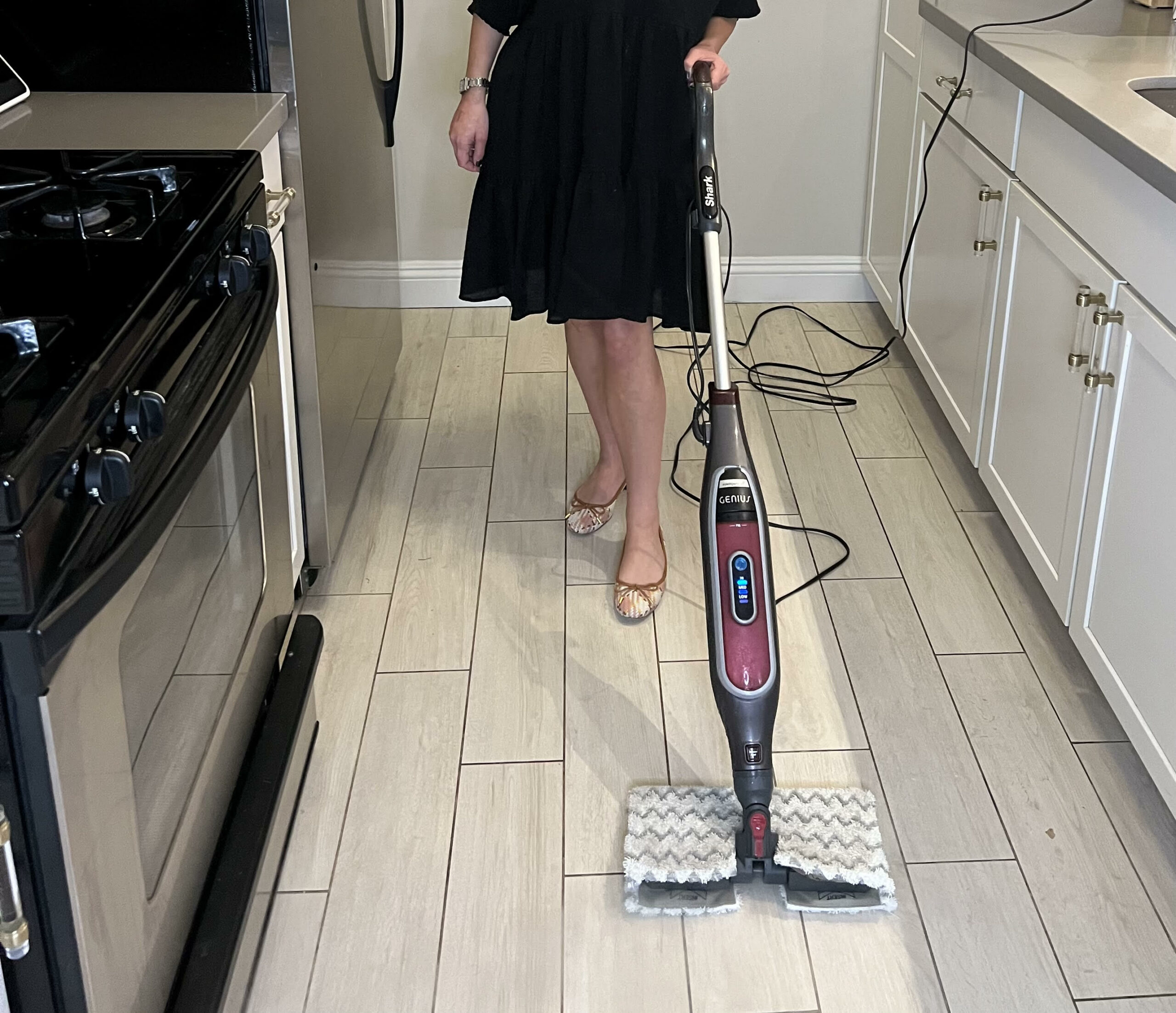 A person using the best vacuum mop combo option to clean the tile floor in a kitchen.