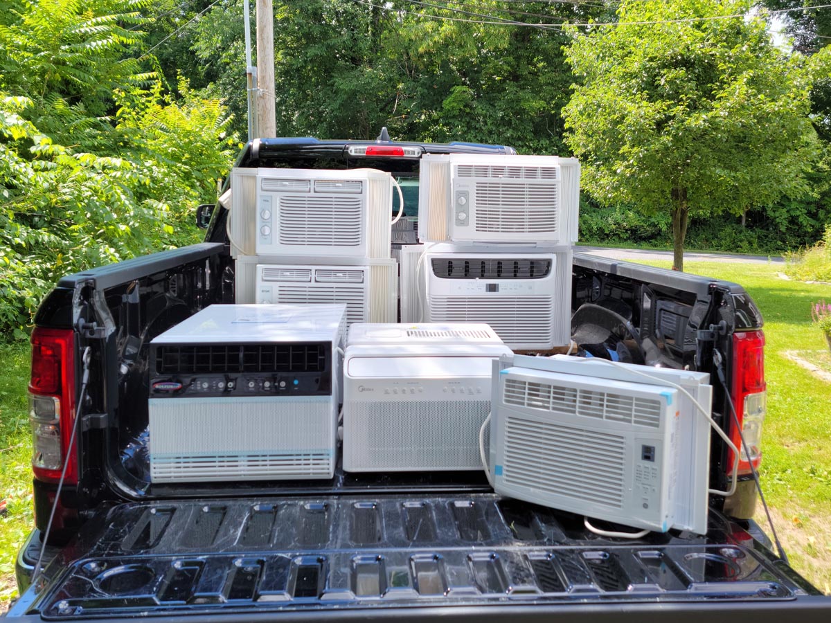A group of the best small window air conditioners placed together in the back of a truck