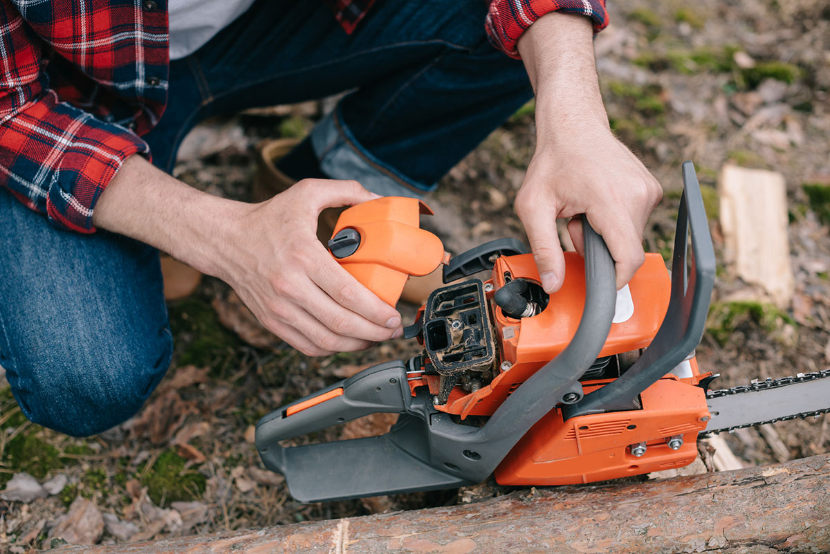 Close up photo of a man's hands replacing the ignition coil on a chainsaw.