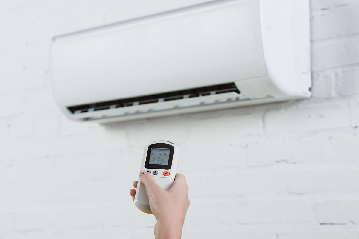 A person using a remote to control the best ductless air conditioner option