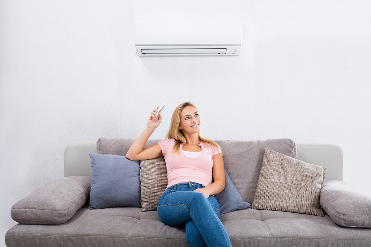 A woman on a couch enjoying the cool comfort of the best ductless air conditioner option