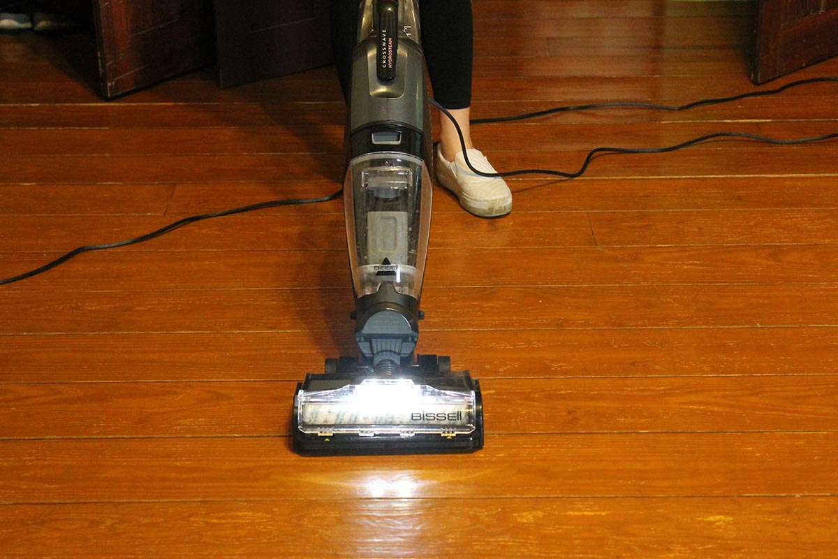 Person cleaning hardwood floor with gray Bissell crosswave wet/dry vacuum
