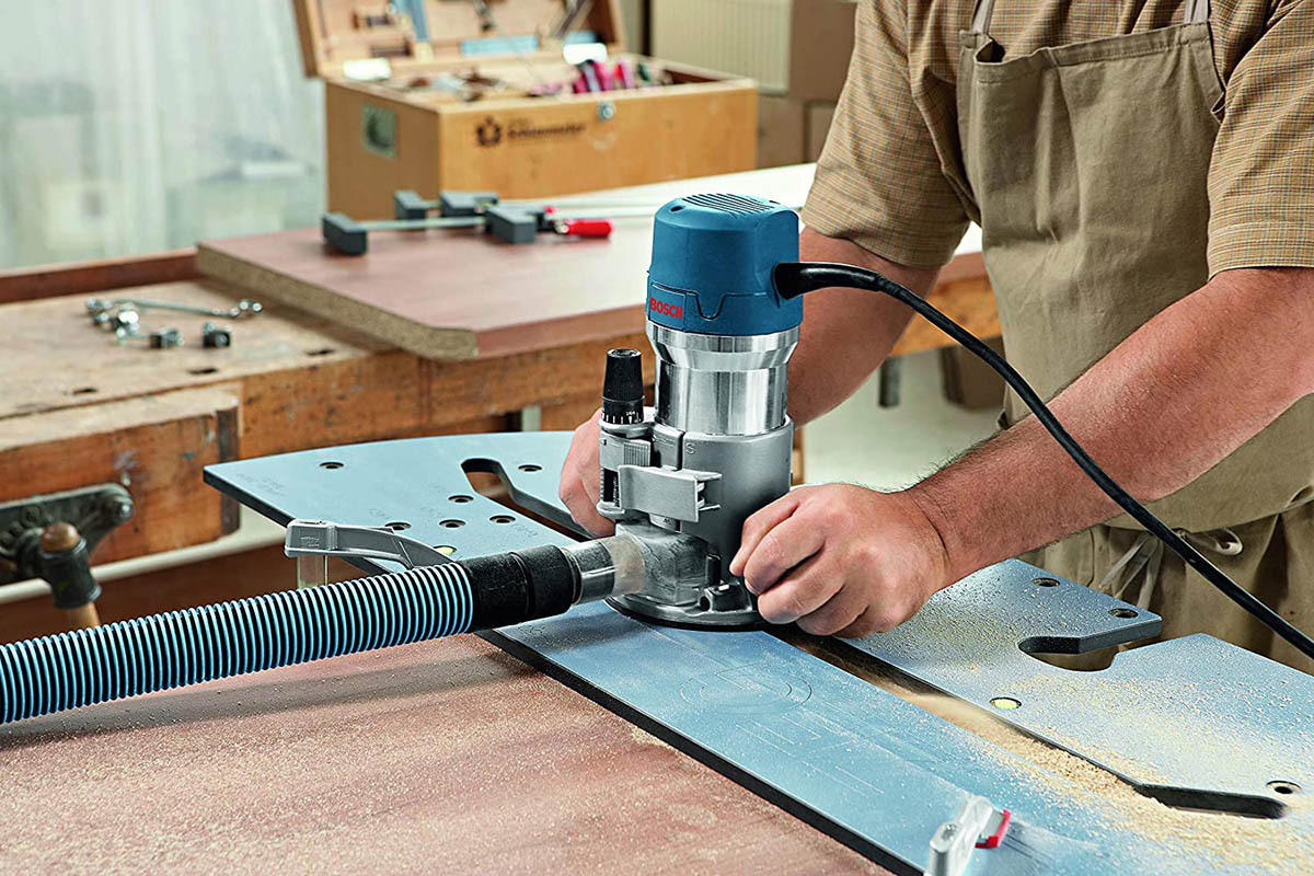 A person using the best wood router for beginners in a workshop stocked with tools.