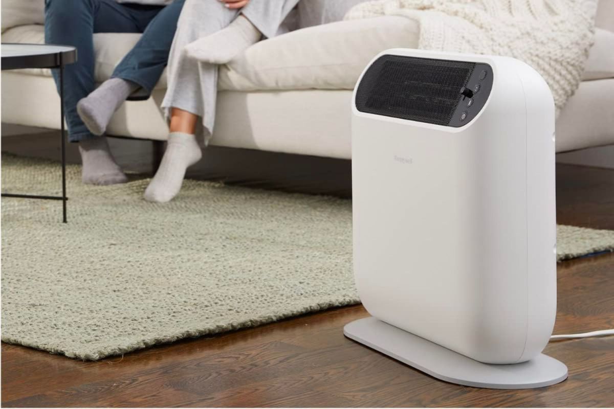 The Best Ceramic Heater on a living room floor keeping two people sitting on a couch in the background warm.