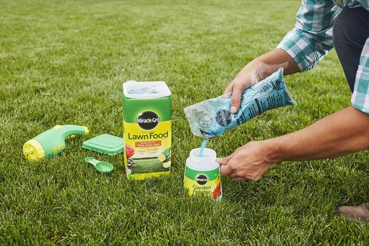Person pouring lawn food into a container on grass