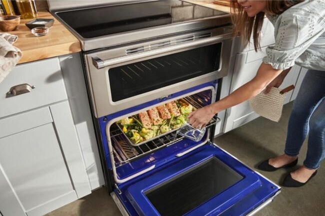 A person lifting a meal out of an induction range
