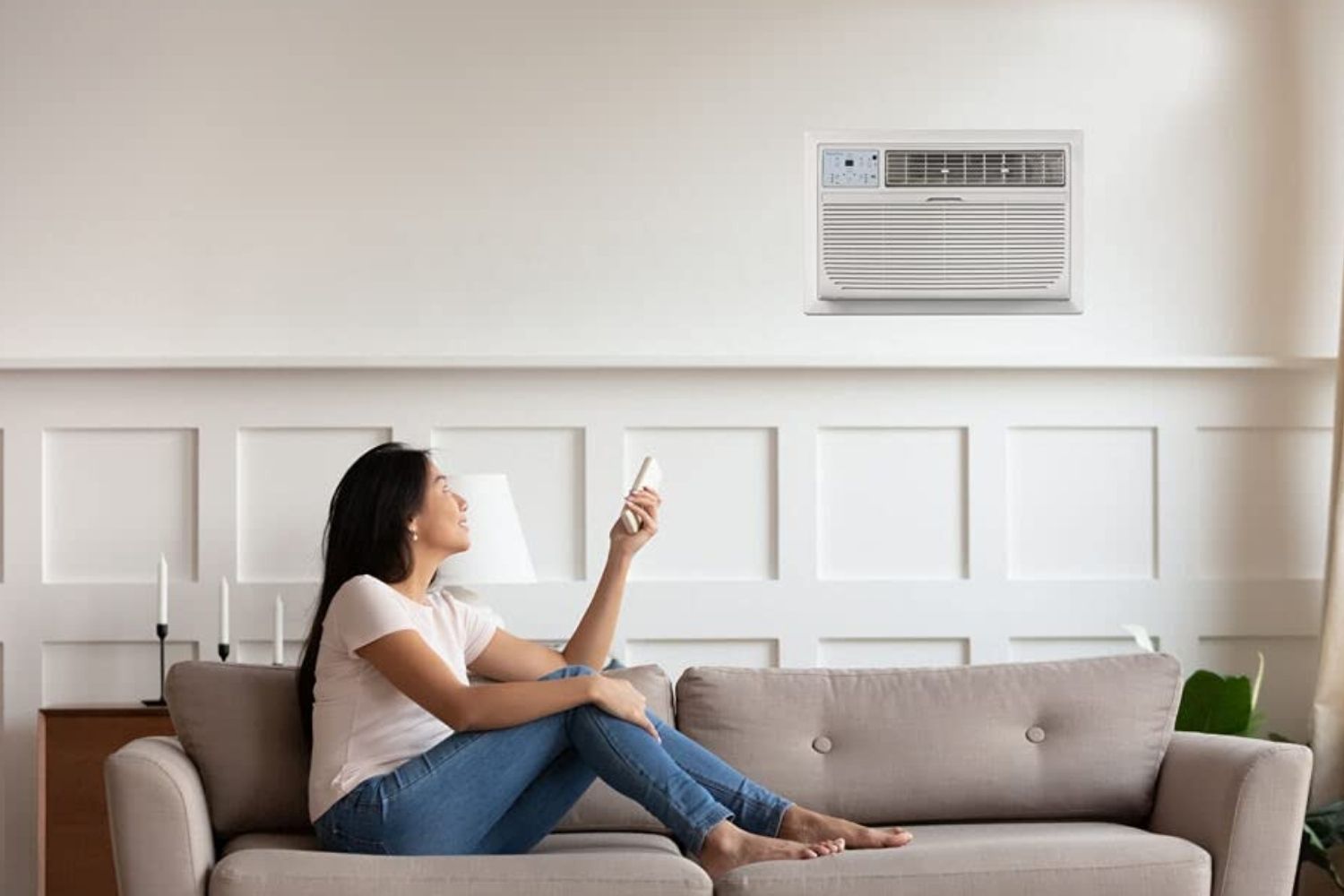 A woman relaxing on the couch with the best through the wall air conditioner cooling the room