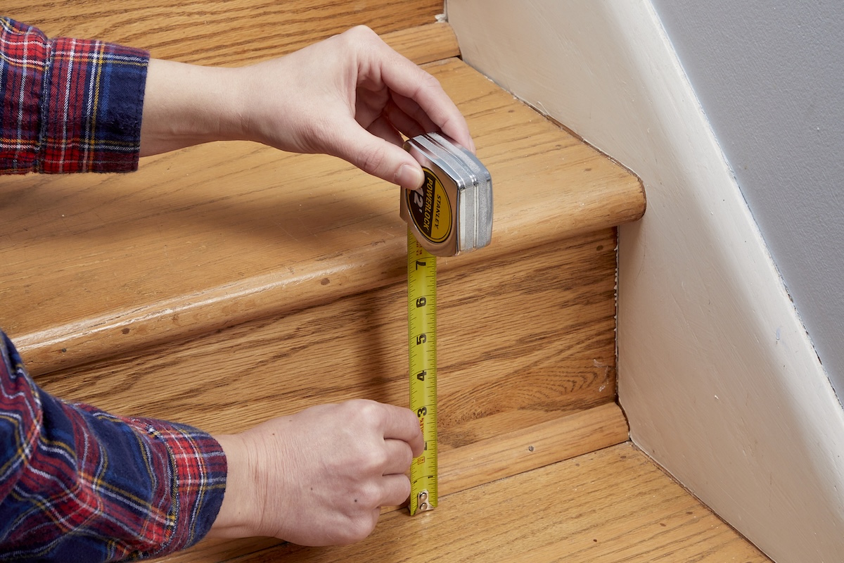 Woman measures rise of a wood stair.