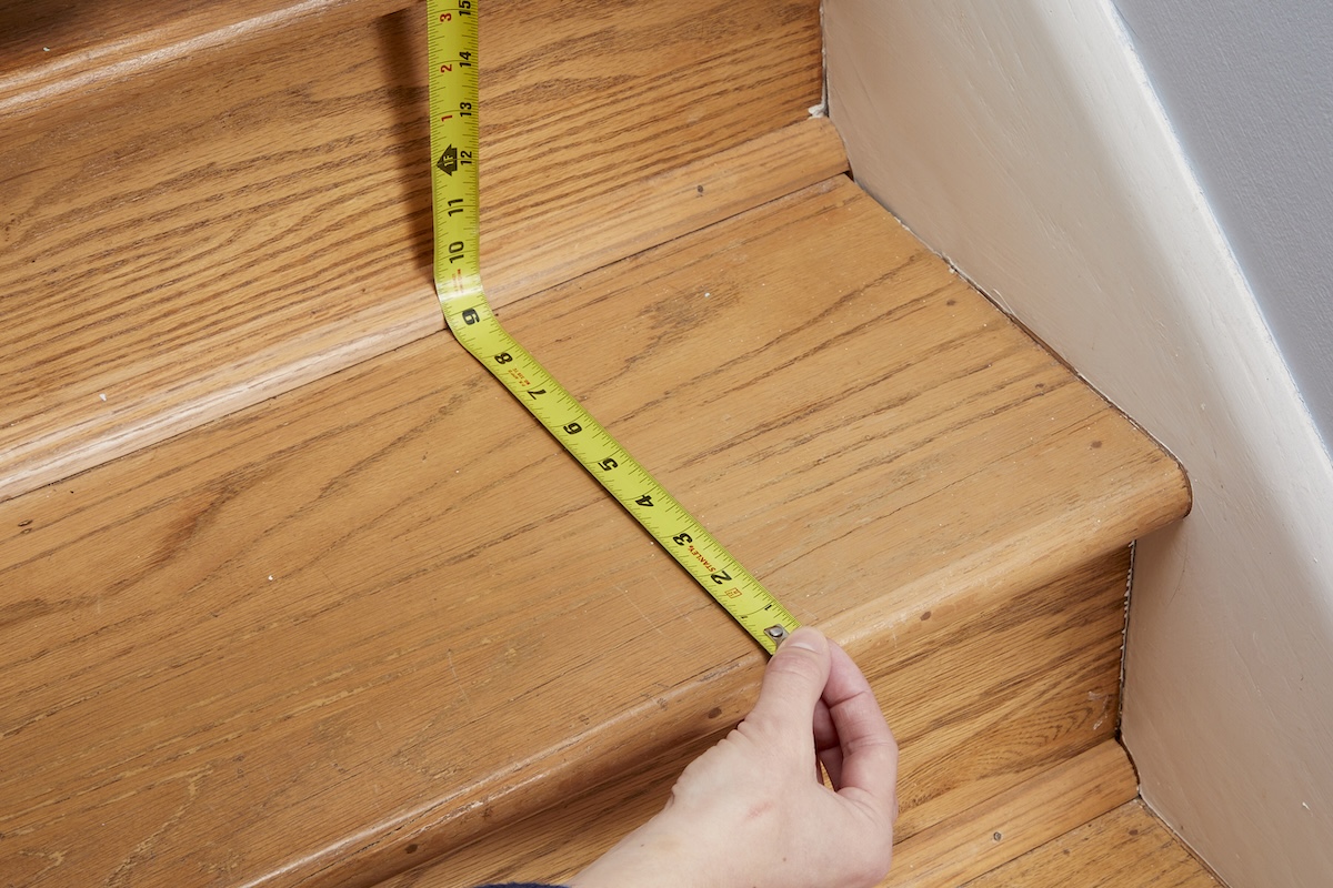 Woman measures run of a wood stair.