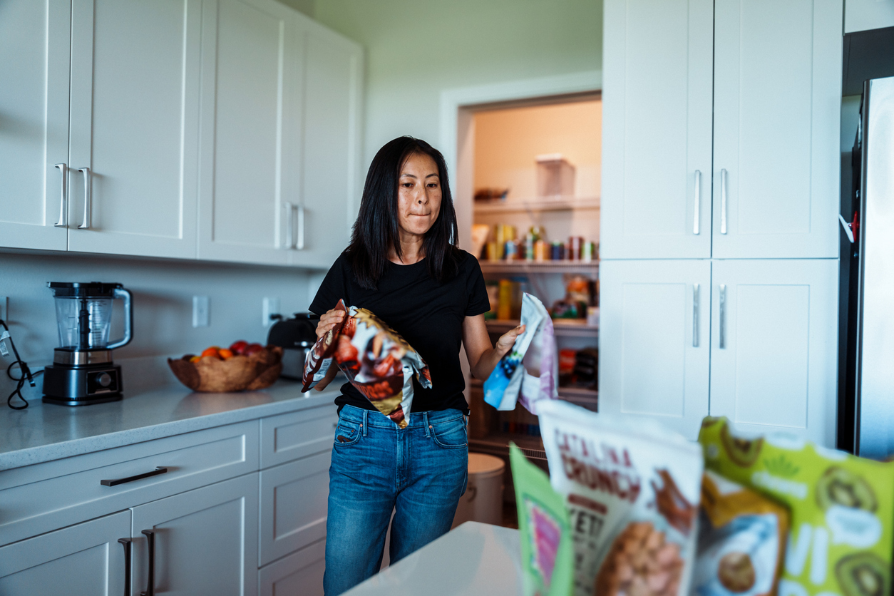 A woman removes bags of food from the pantry.