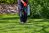 Man from waist down using a pump sprayer to apply herbicide to a yard.