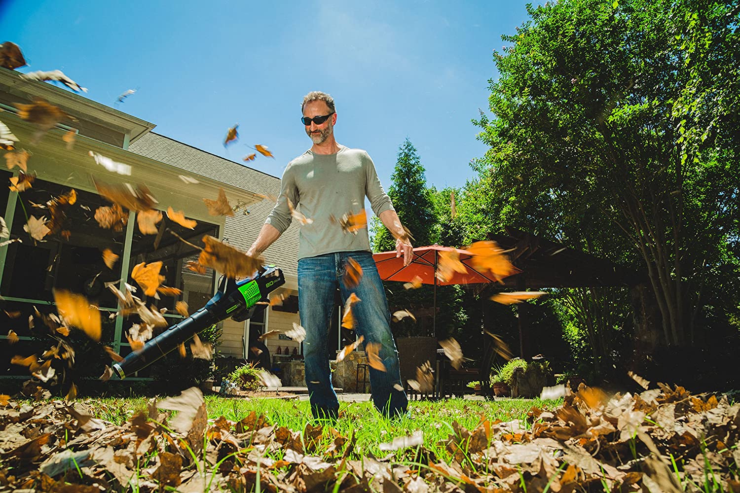 A person using the best cordless blower option to clear leaves from a yard