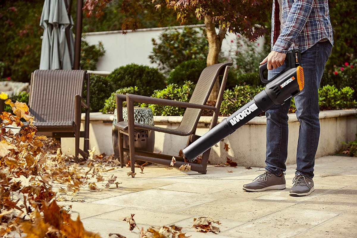 A person using the best cordless blower option to clear leaves from a patio
