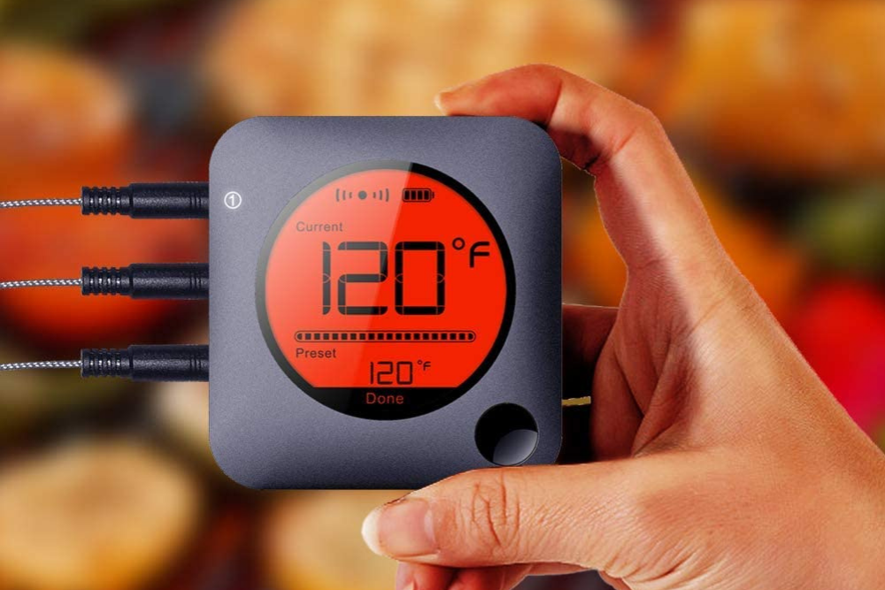 A person holding the best wireless meat thermometer that shows a temperature of 120 degrees Fahrenheit.