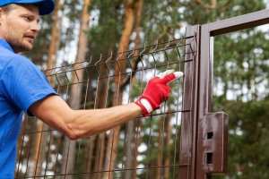 A close up of a worker installing a brown fence.