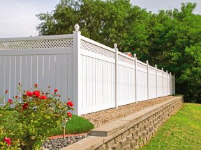 A view of a white vinyl fence on a clear day.
