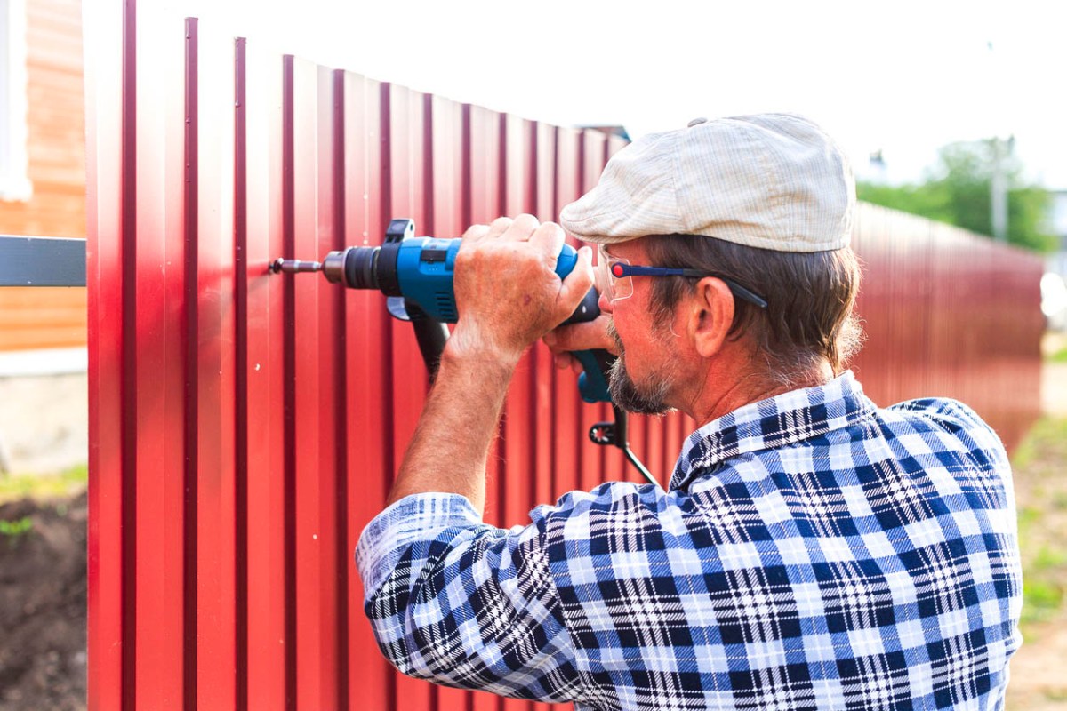 A worker installs a red fence.