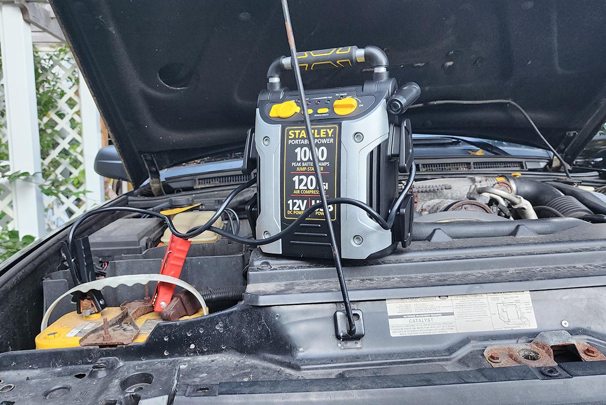 The best jump starter with air compressor option on a car engine hooked up to the battery