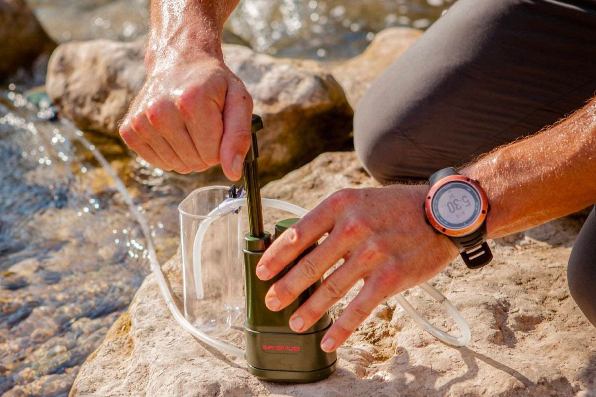 A closeup of someone using the best portable water filter option to filter water from a stream