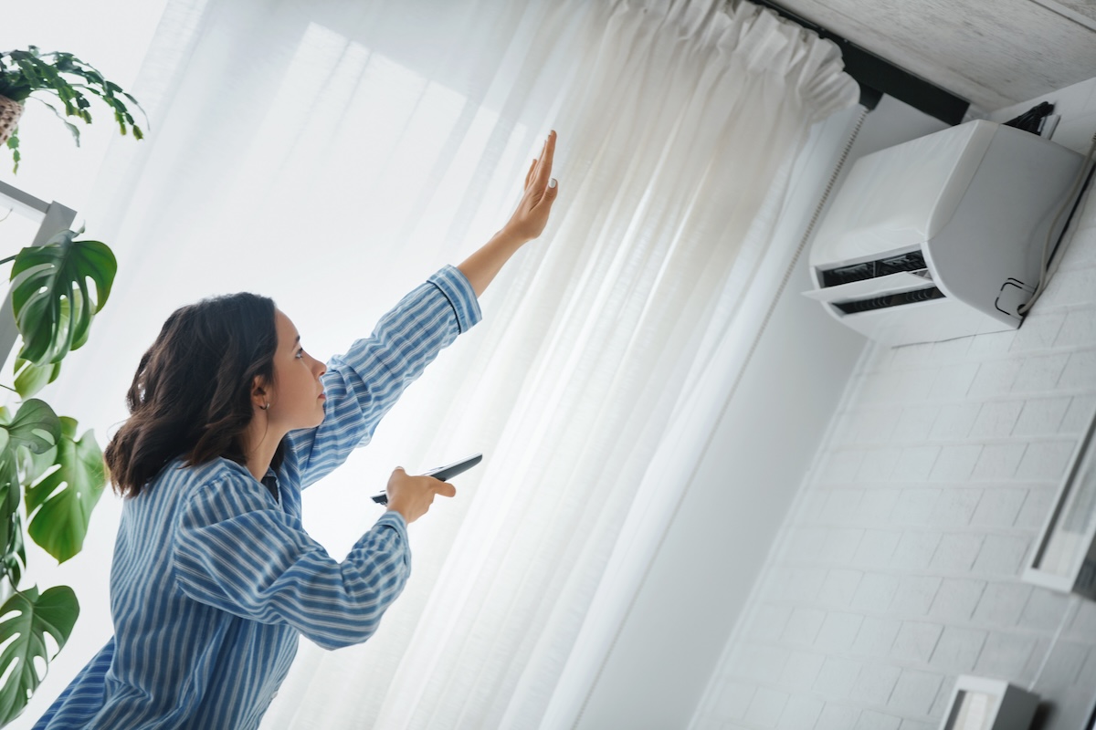 A woman uses a remote to turn on her AC unit.