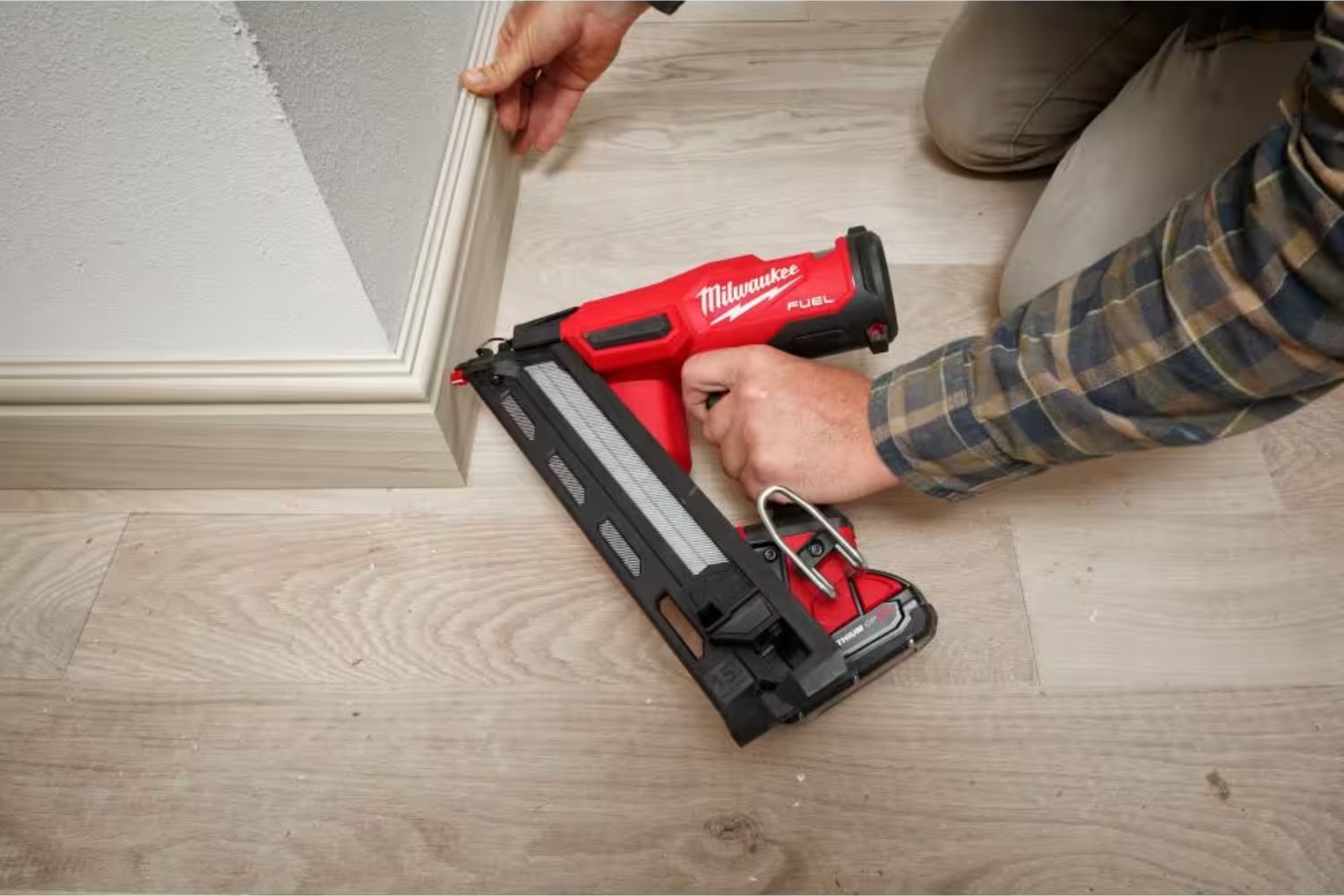 A person using the best cordless finish nailer option to install a baseboard