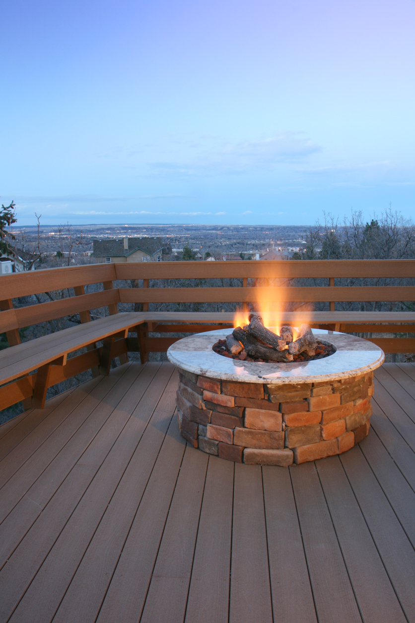 Deck and fire pit overlooking city lights at dusk. Focus on the fire pit