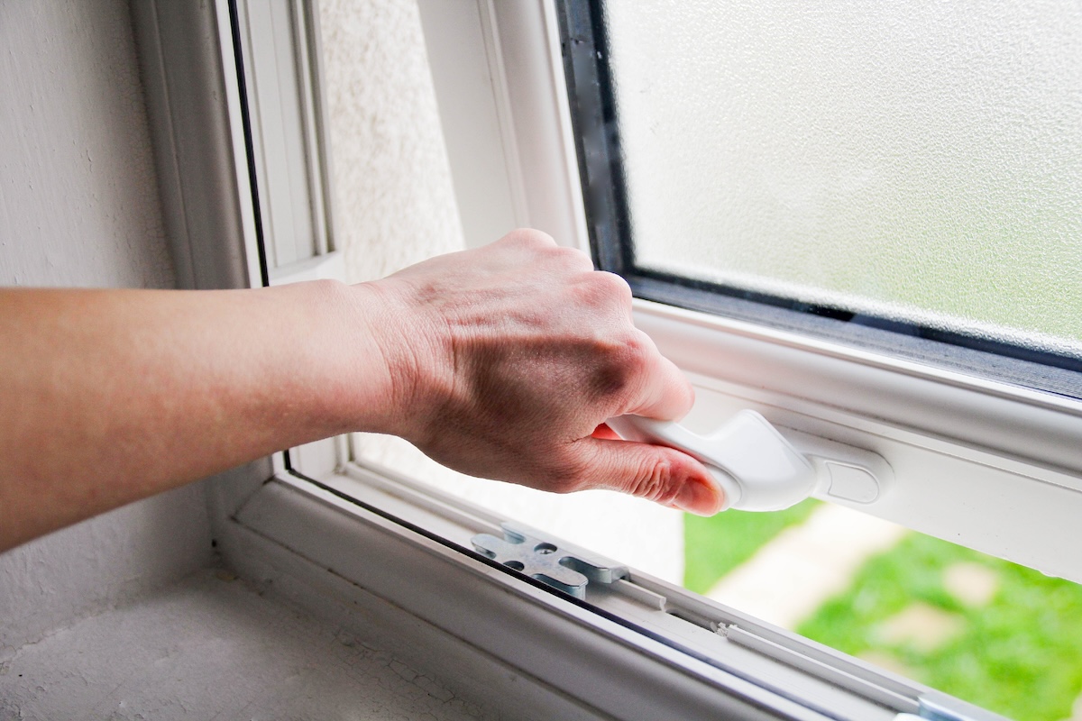 Hand opening the crank on a bathroom window.