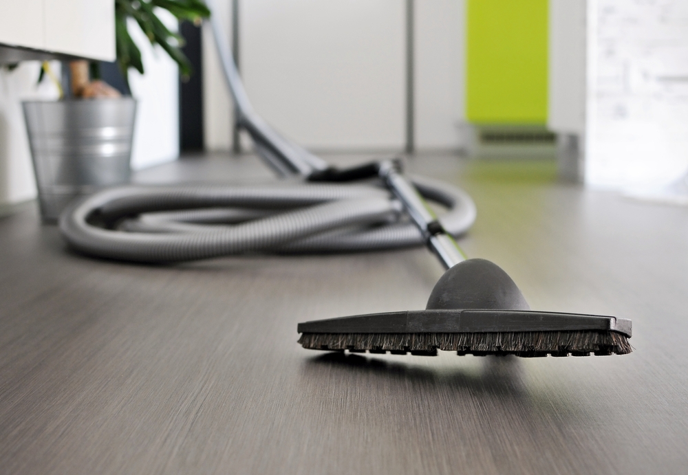 The cleaning head and long winding cord of the best central-vacuum system laid out on a laminate floor.