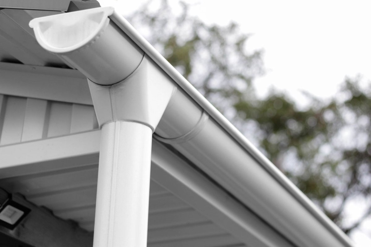 Closeup view of white rain gutter and downspout on home.