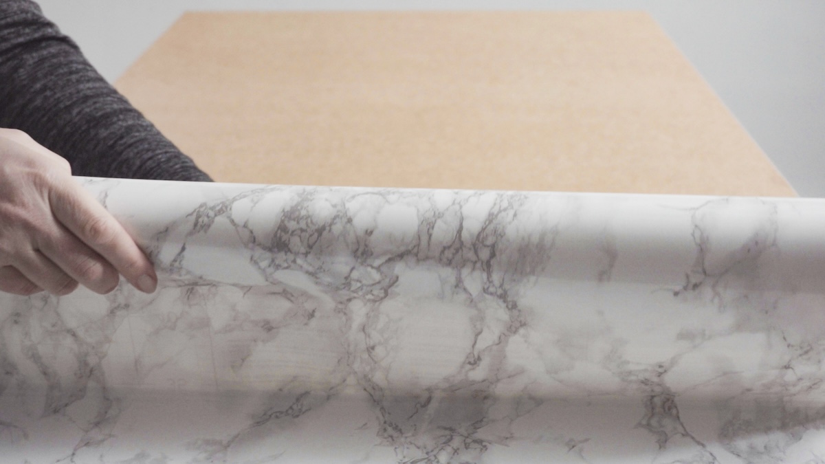 Laying ahesive countertops onto a wooden counter.