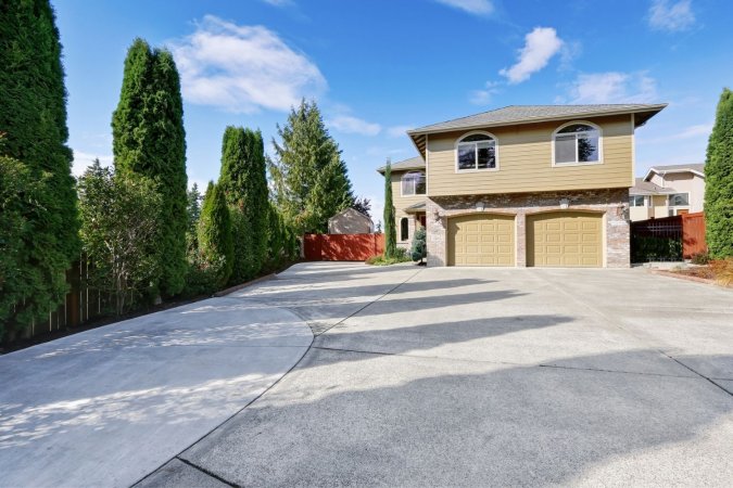 A view of a concrete driveway leading to beige house.