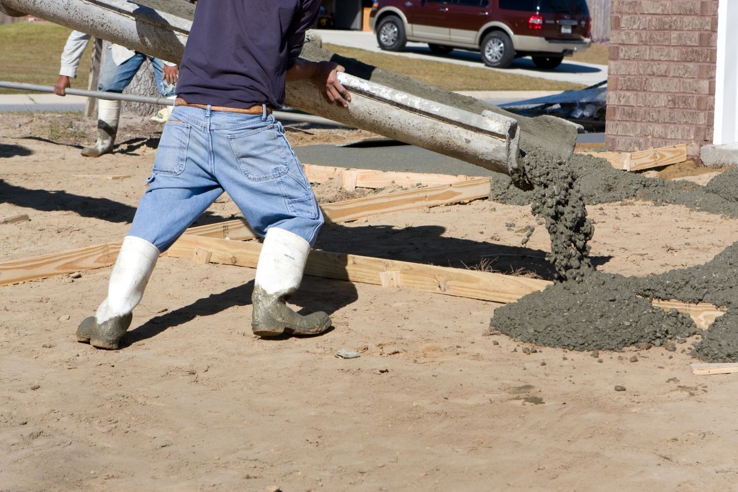 A worker pours concrete in a driveway.