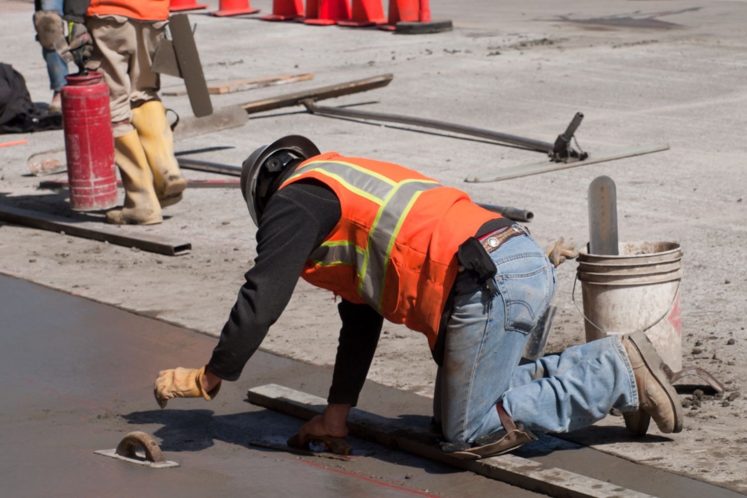 A worker levels concrete in a driveway.