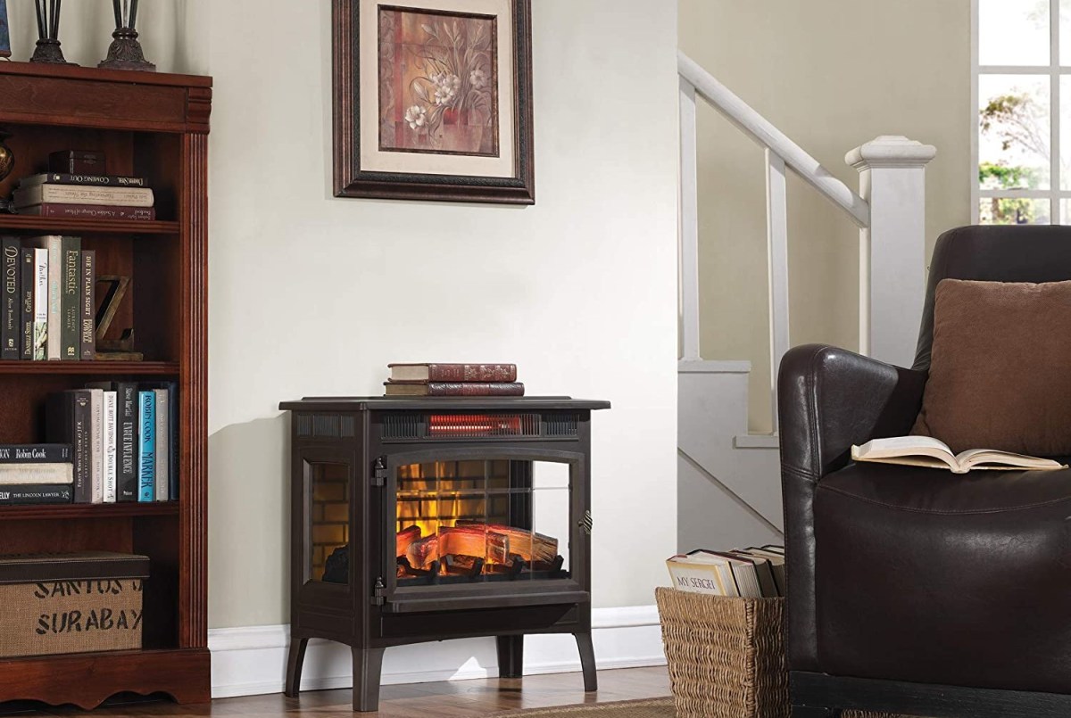 The best electric fireplace heater with a warm, glowing fire inside while installed on a living room wall and in use to hold books.