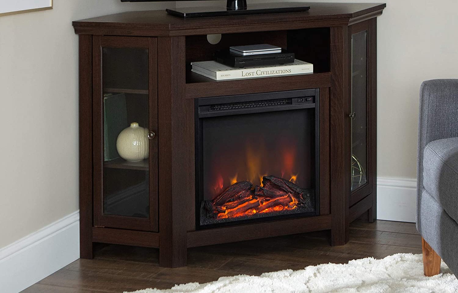 The best electric fireplace heater tv console displaying a warm fire, a tv, books, and other decor items.