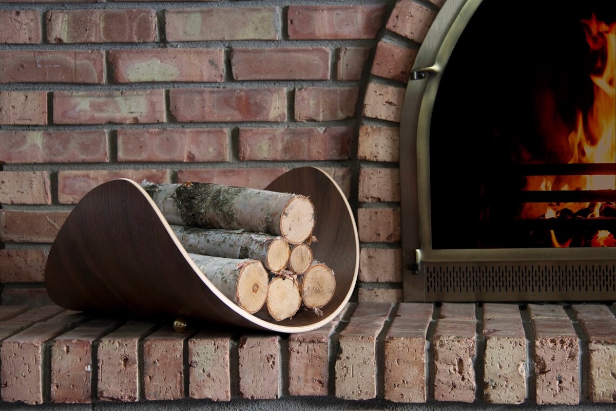 A curved firewood storage container next to an indoor fireplace.