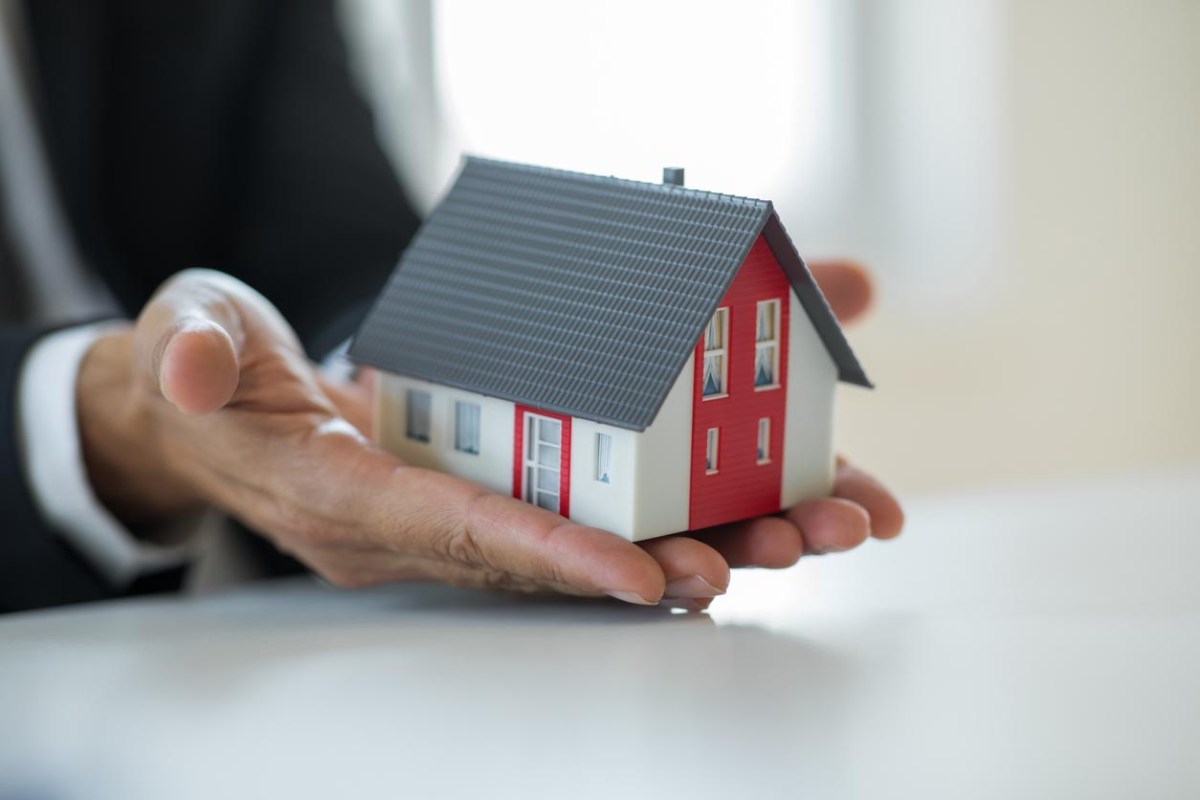 A close up of someone holding up a small home model.