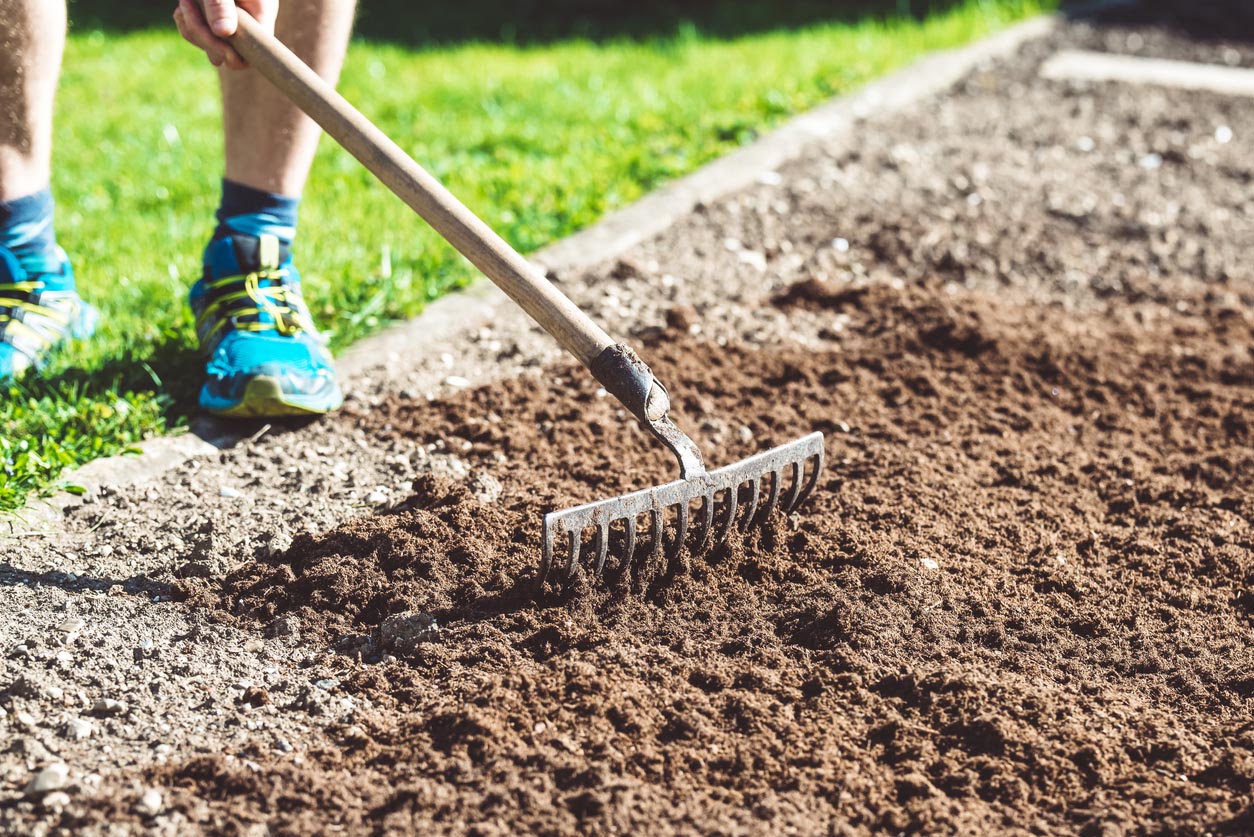 A close up of someone using a rake to level ground.
