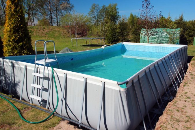 An above ground pool on a lawn on a bright day.