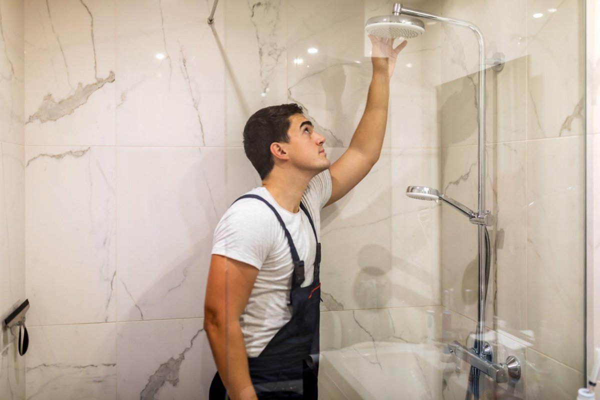 A worker in blue overalls renovates a shower.
