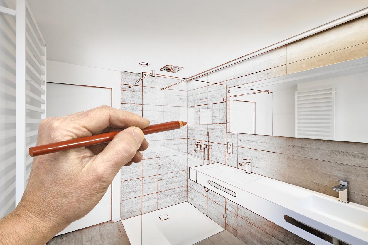 A close up of a hand holding a red pencil and using it to design a new shower. 