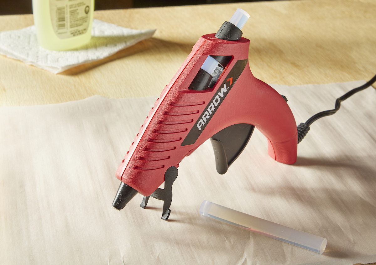 Setting up a hot glue gun for use, with glue gun on its stand on a work surface.