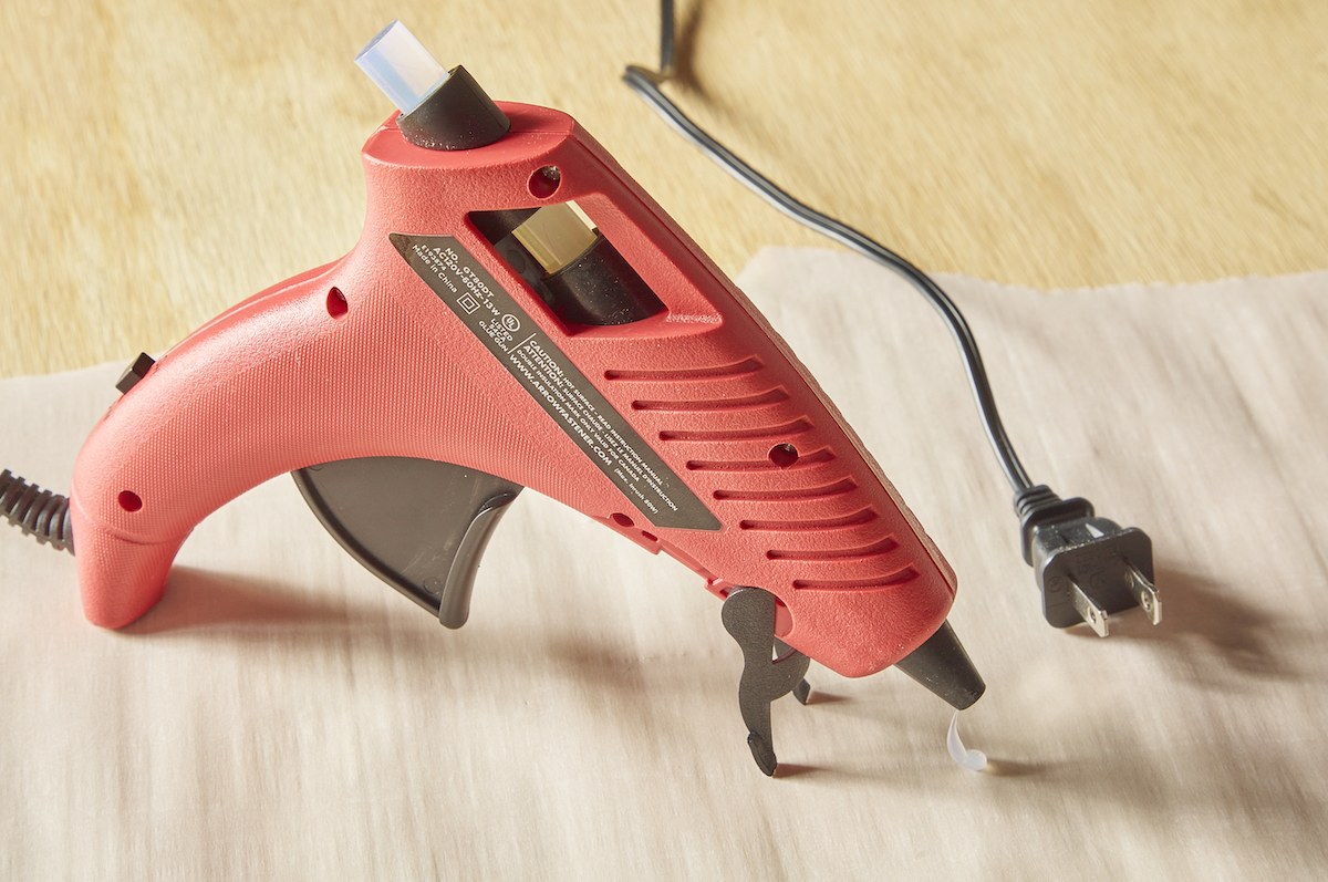 Allowing a hot glue gun to cool by unpluging it and leaving it upright on its stand.