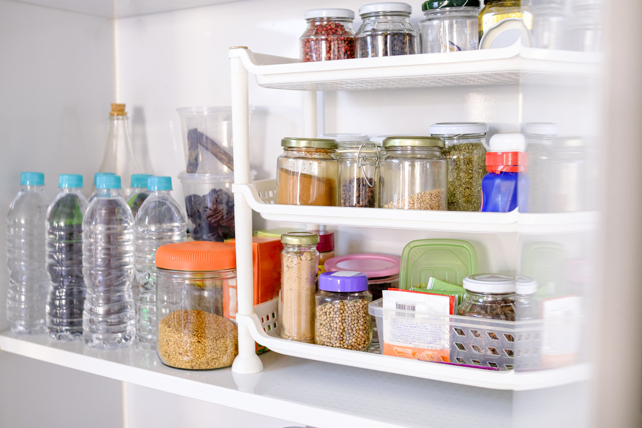 Pantry shelves that are well stocked with jarred dry goods, spices, and water bottles.