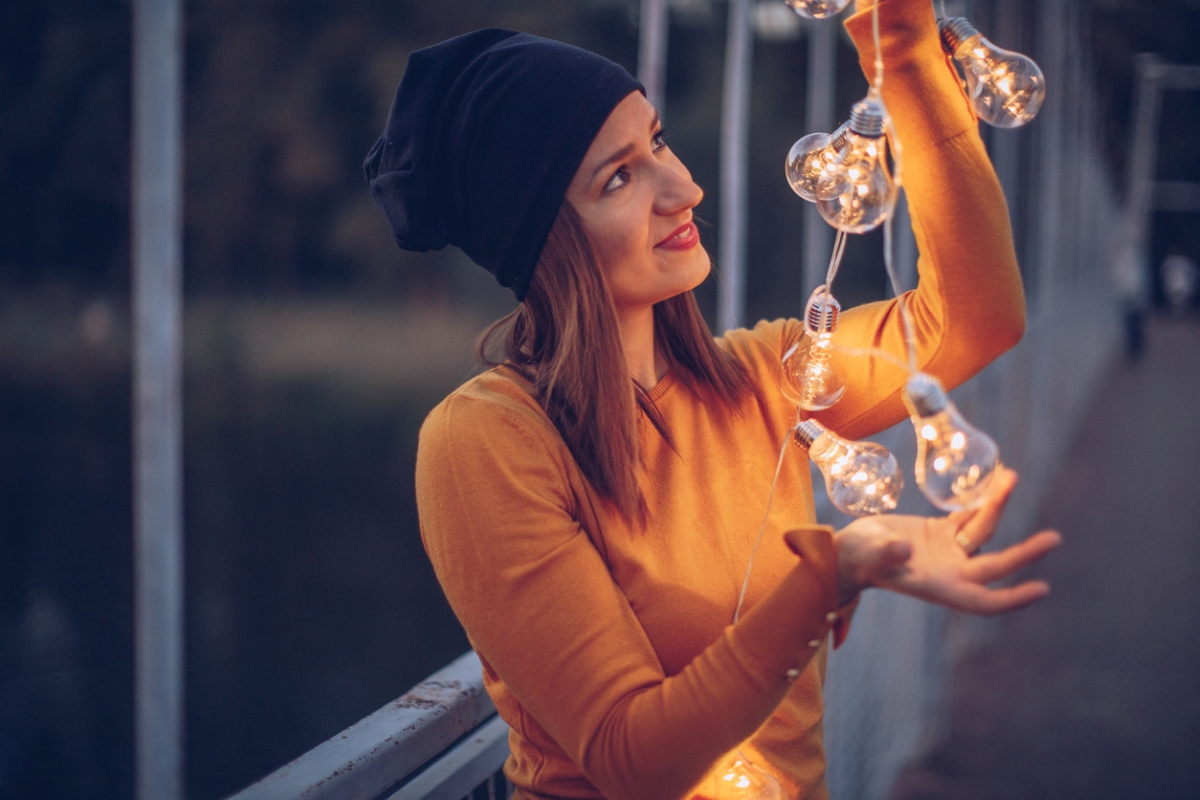 Woman looking at lit string lights in her hands