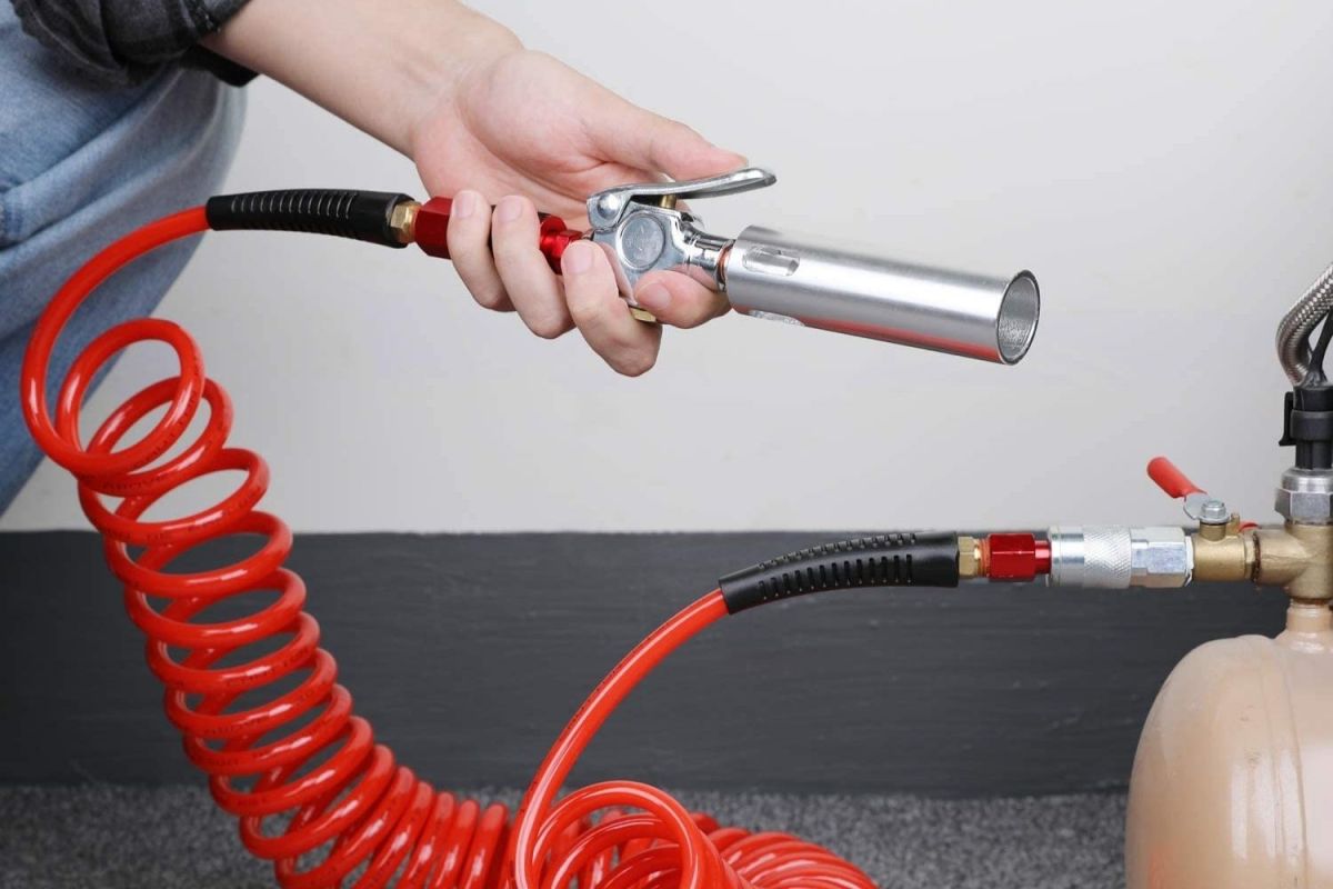 A person holding the included universal coupling attached to the Hromee ¼-Inch 25-Foot Polyurethane Recoil Air Hose.