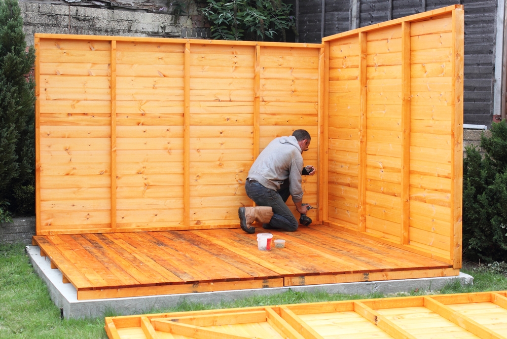 A person works on a partially constructed wooden shed.